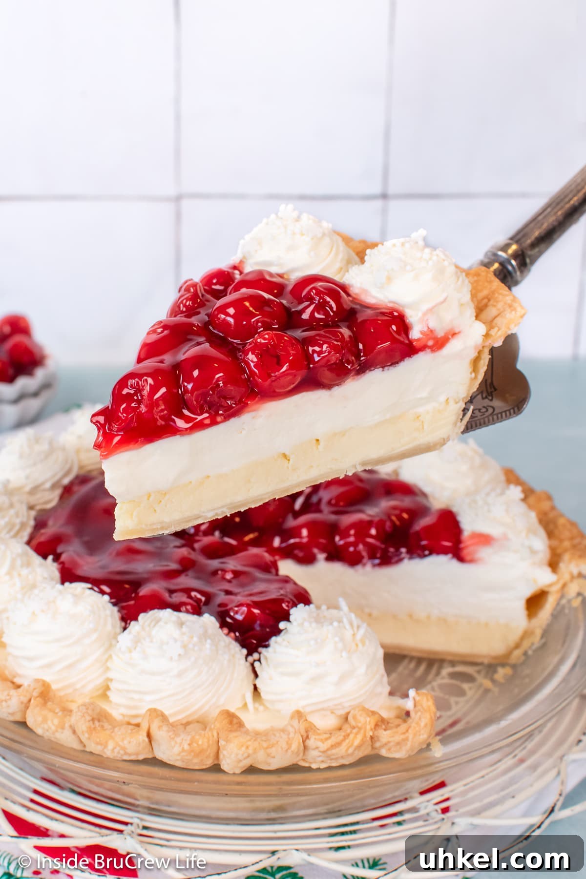 Classic Cherry Cream Cheese Pie Recipe 7 A piece of cream cheese pie with cherries being lifted out of the pan.