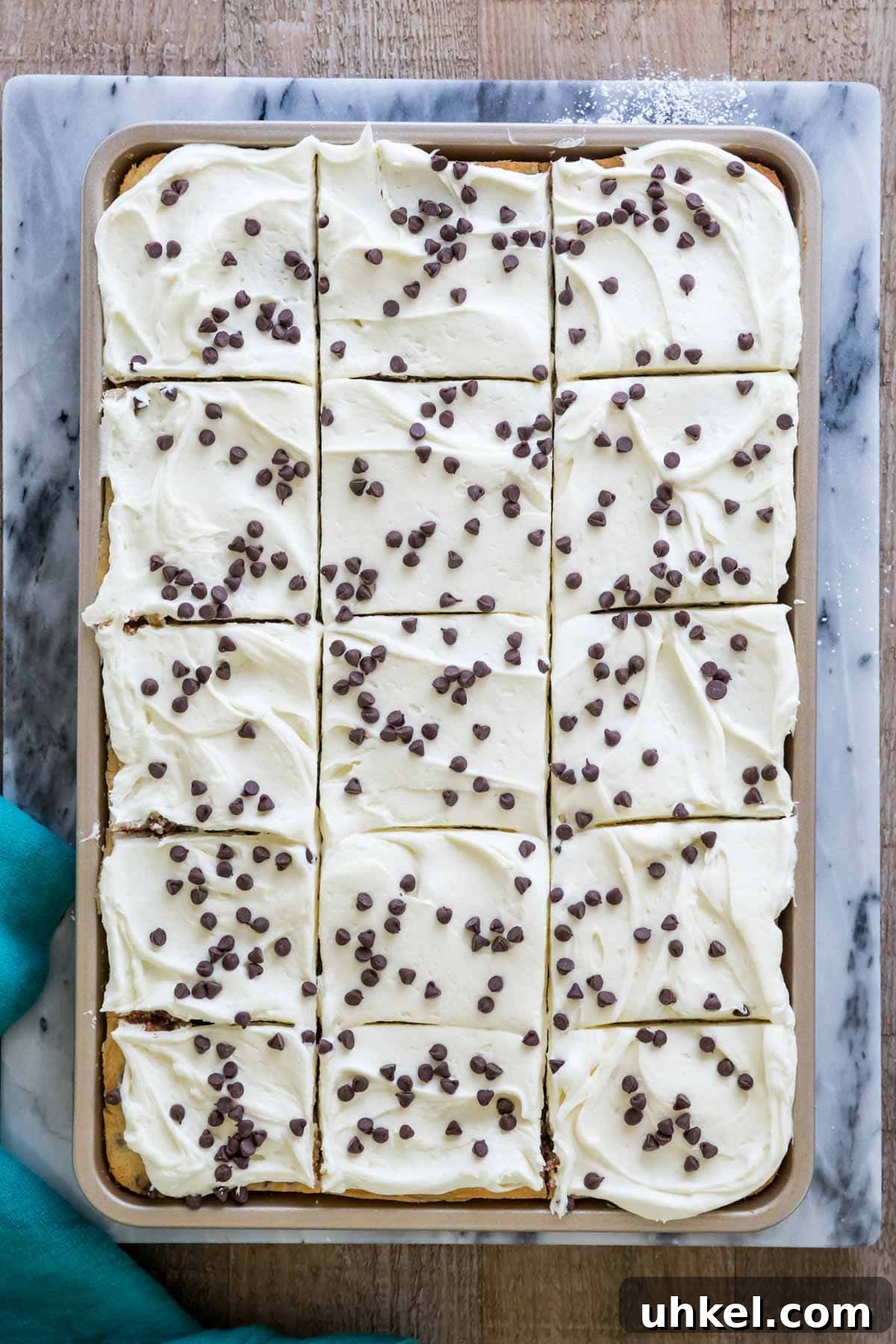Classic Chocolate Chip Sheet Cake Recipe 5 Overhead view of chocolate chip sheet cake baked in a gold jelly roll pan. Iced with white frosting and topped with chocolate chips