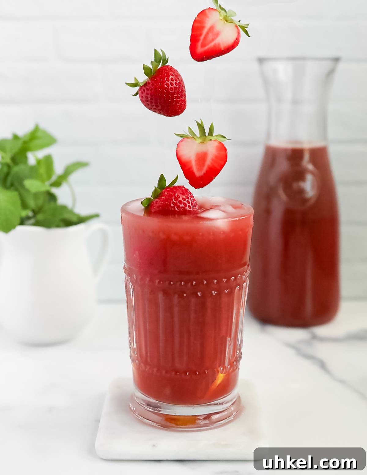 Homemade Strawberry Acai Lemonade 2 A picture of pink lemonade with strawberries falling into the glass