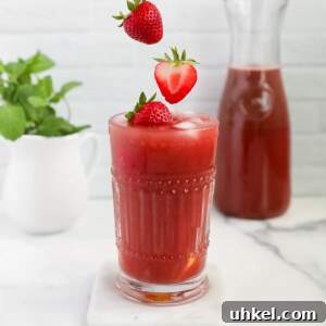 Homemade Strawberry Acai Lemonade 11 Three strawberries falling into a glass filled with pink lemonade
