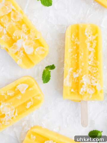 An overhead picture of yellow/orange mango popsicles. They are covered in crushed ice