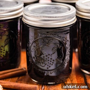 sealed jars of elderberry syrup with cinnamon sticks in front.