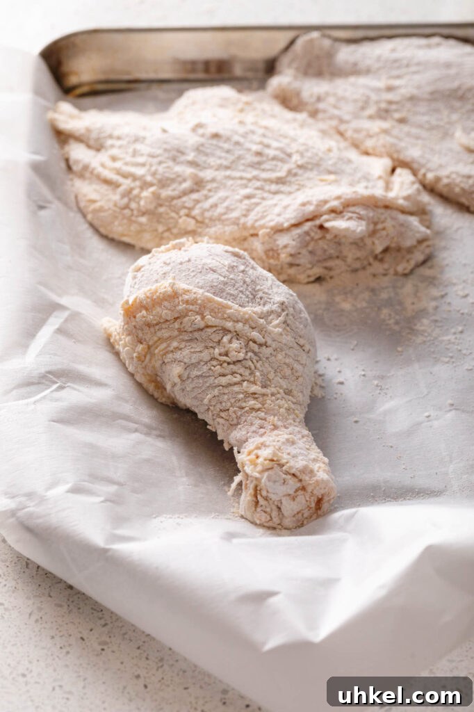 Crispy Fried Chicken Without Buttermilk 8 flour coated chicken pieces on a parchment lined sheet pan